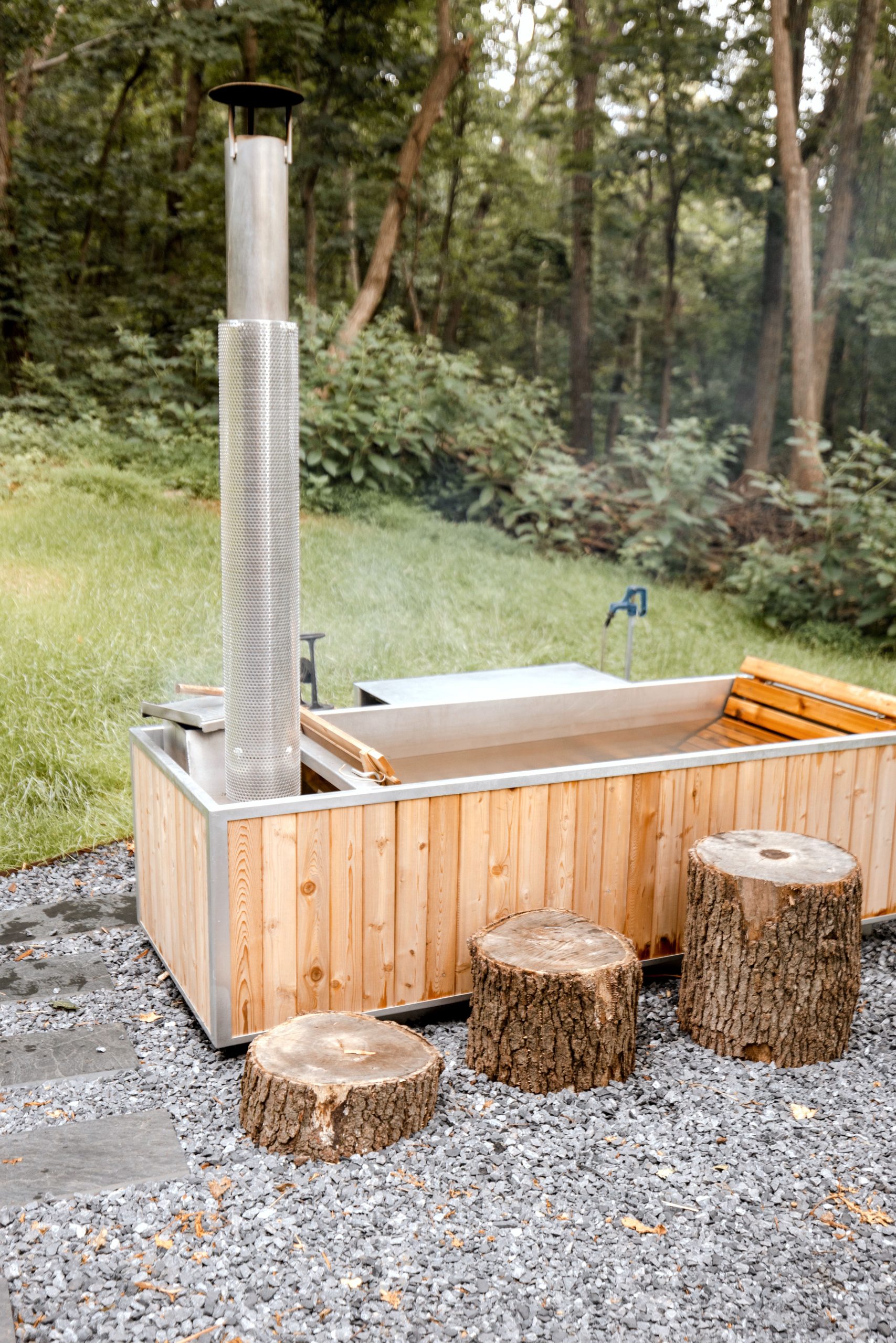 Moderní dřevěná koupací káď s externími kamny a nerezovým komínem na zahradě