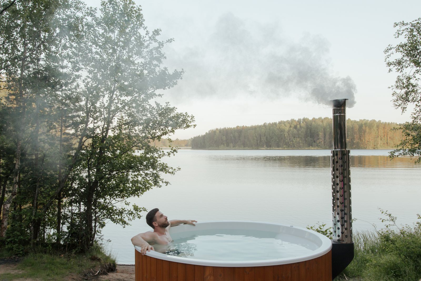 Muž relaxující ve venkovní vířivce u jezera při hydromasáži
