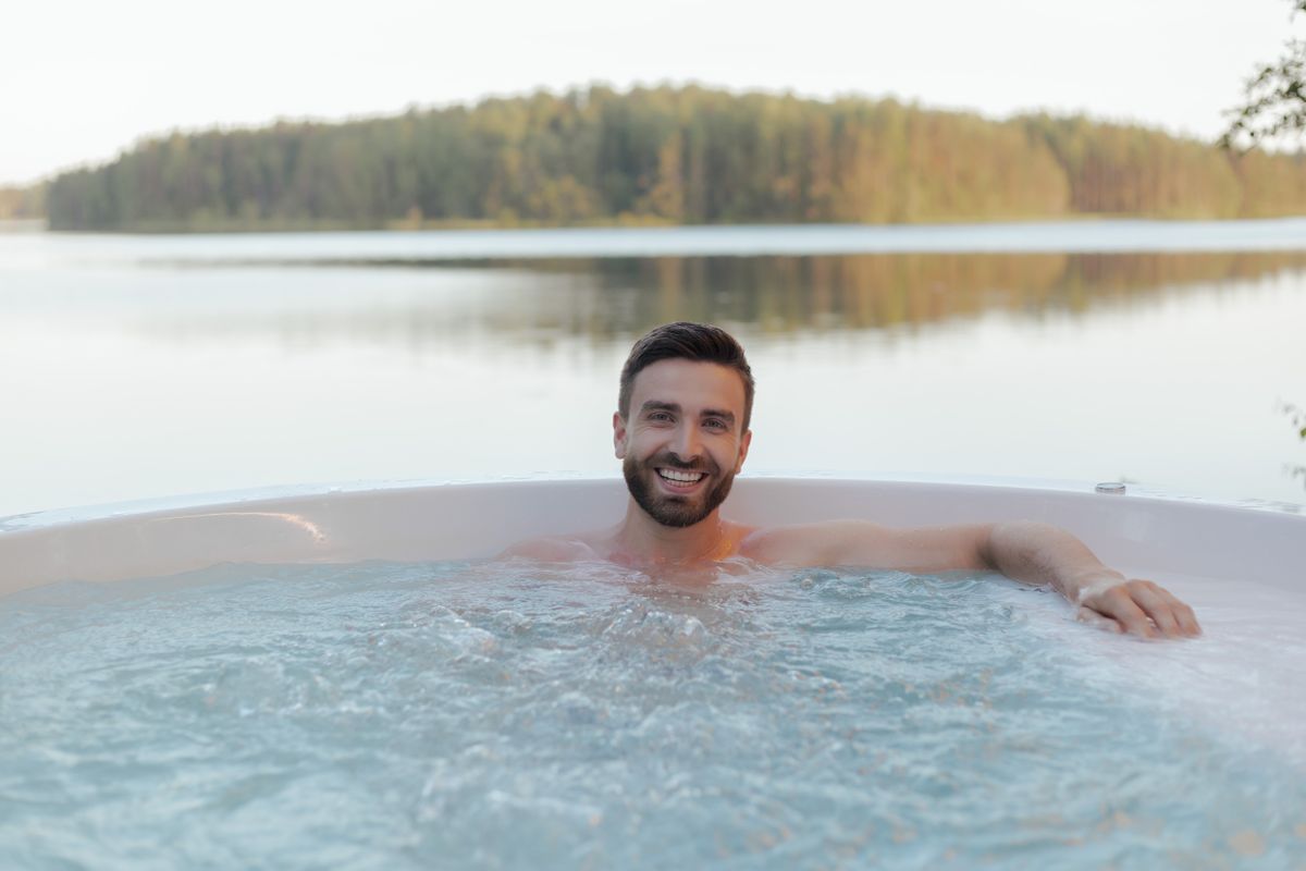 Muž relaxující v malé kruhové vířivce u jezera