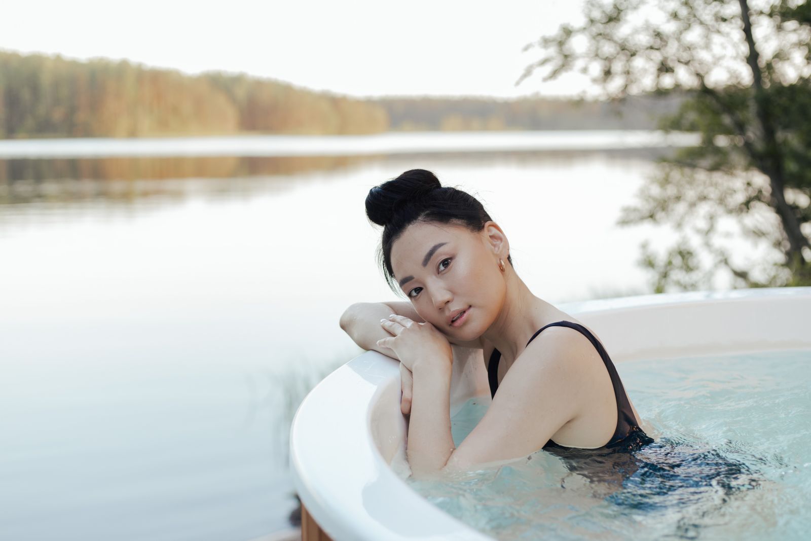 Žena relaxující ve venkovní vířivce s výhledem na jezero