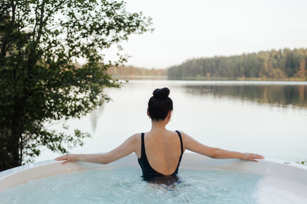 Žena relaxující ve venkovní vířivce s výhledem do krajiny