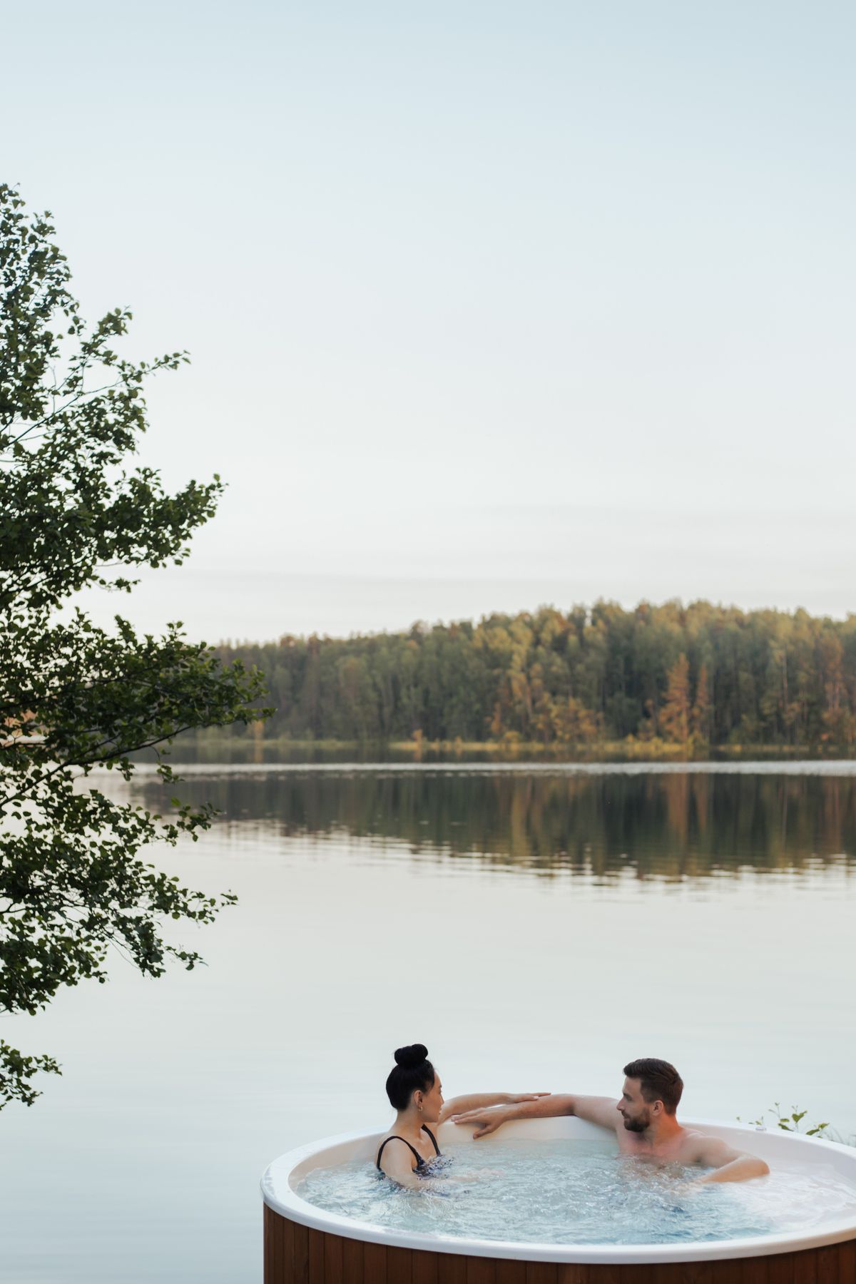 Pár relaxující ve vířivce s výhledem na jezero