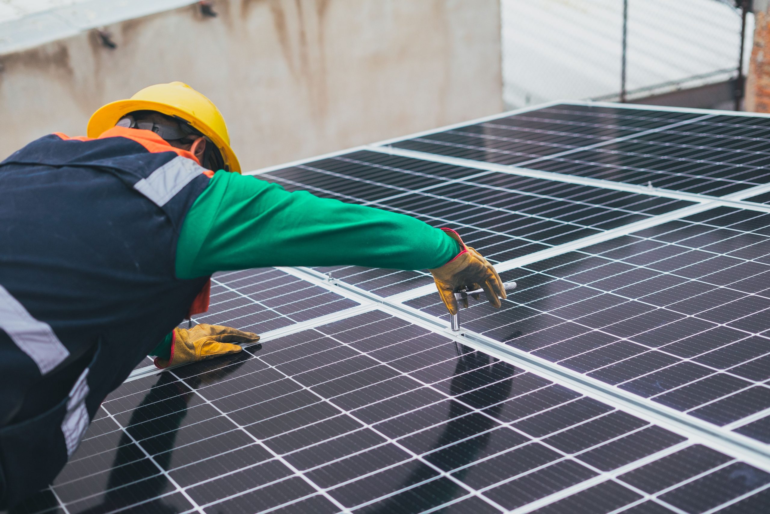 Technik instalující fotovoltaické panely na střechu