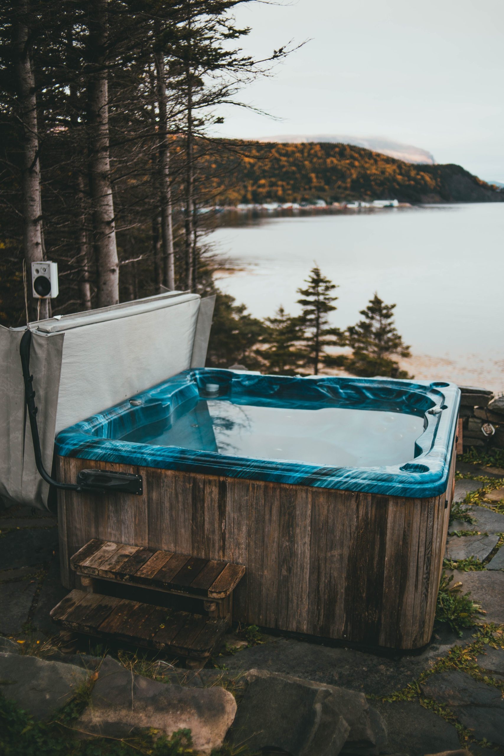 Dřevěná venkovní vířivka s výhledem na jezero a les, prostředí pro domácí relaxaci