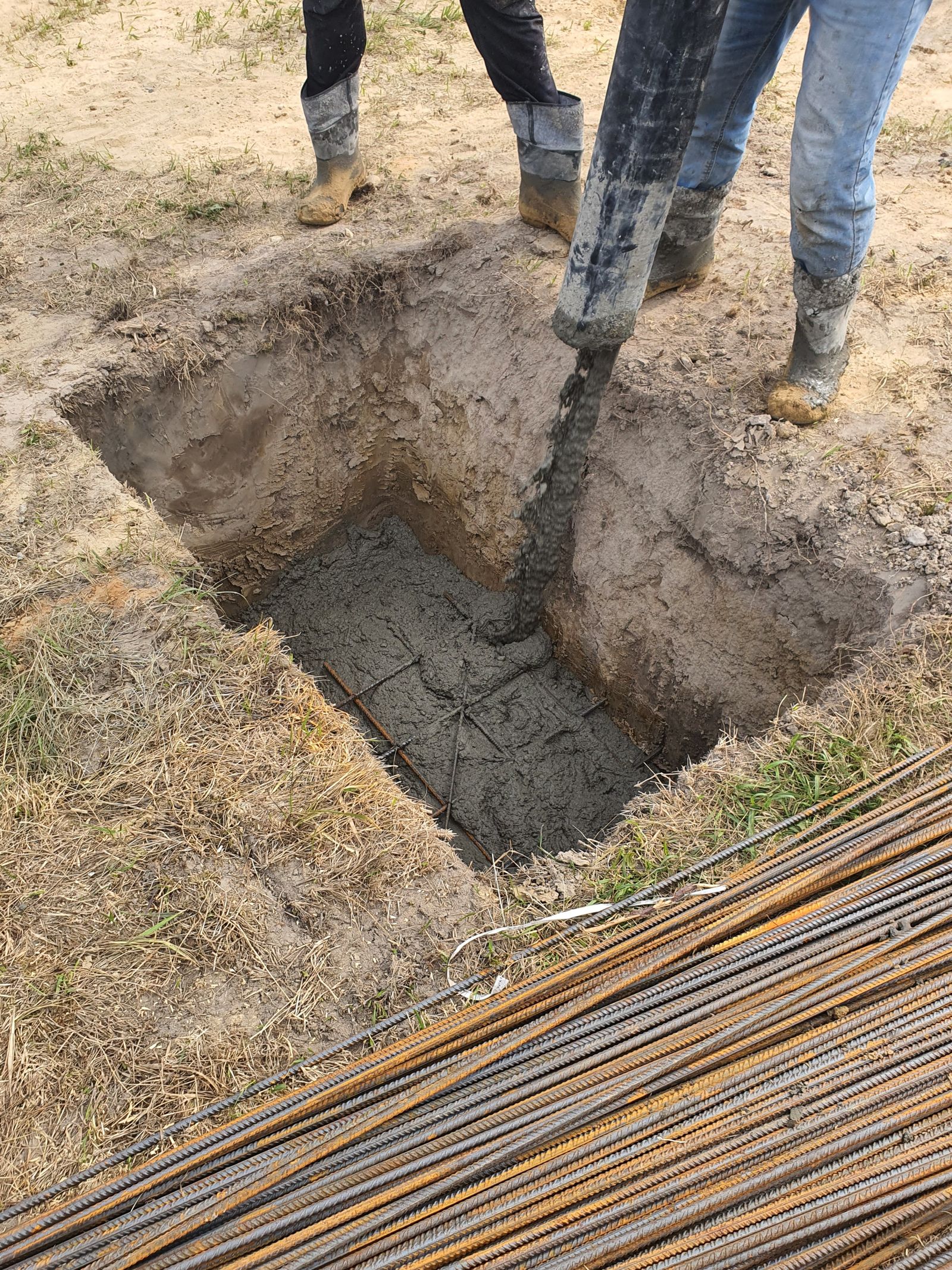 Betonáž vyztuženého základu na stavbě, čerstvý beton se lije mezi ocelovou výztuž
