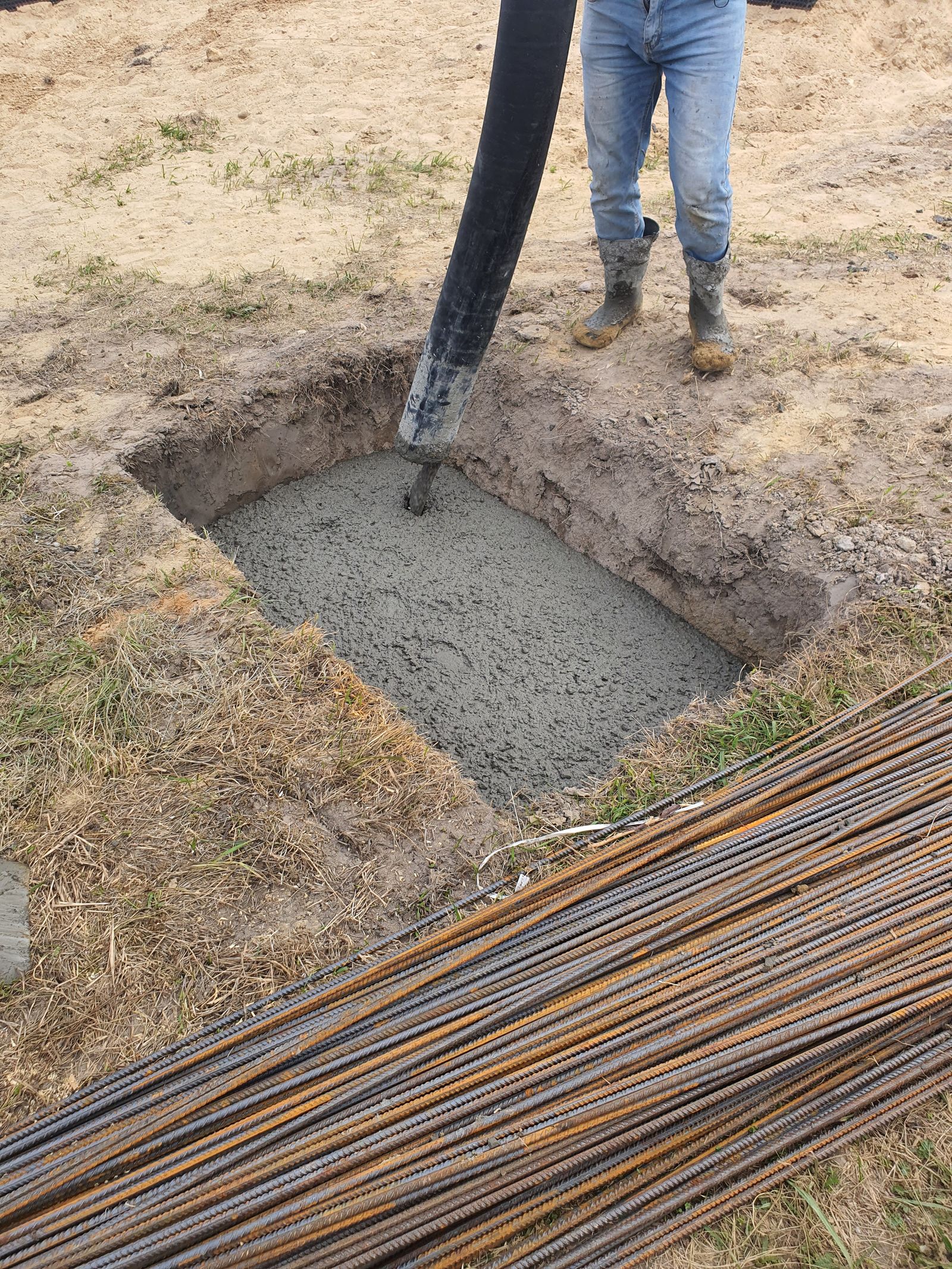 Ukládání betonu do základové jámy s viditelnou výztuží — betonáž po vrstvách
