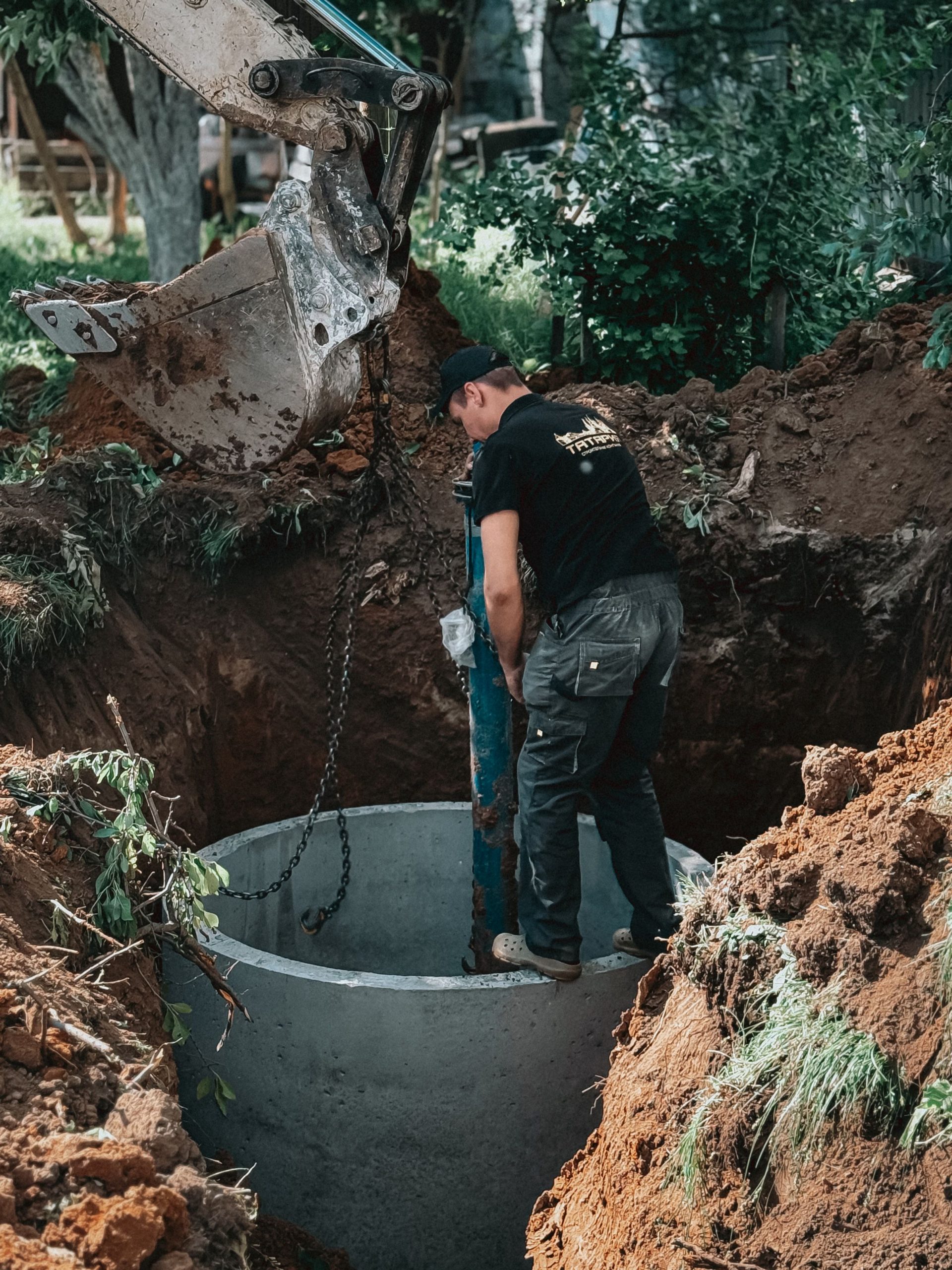 Pokládka betonového potrubí do výkopu jako součást drenážního systému
