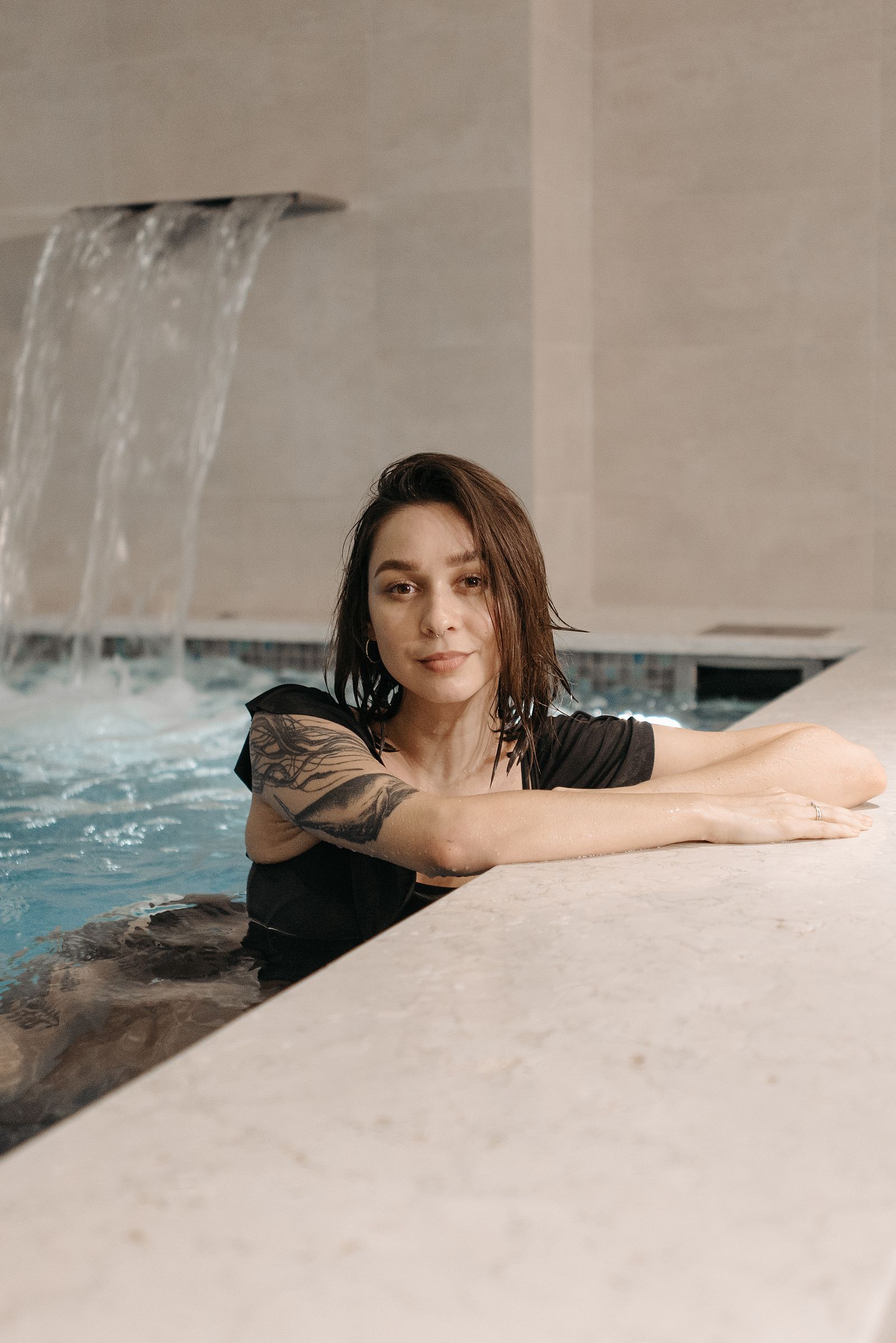 Žena odpočívá u okraje vířivé lázně s vodním chrličem